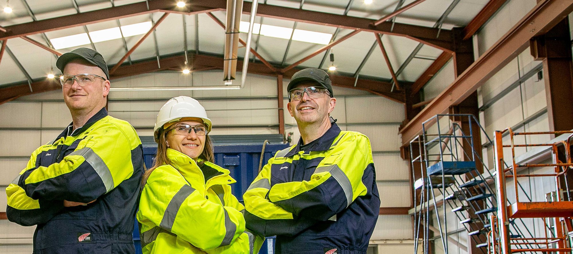 Three OEG workers with arms folded in a workshop